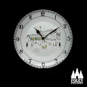May include: White ceramic clock with black numbers and hands. The clock face features a black and white illustration of a stadium with people in the foreground. The text "CARROW ROAD" is printed on the clock face.