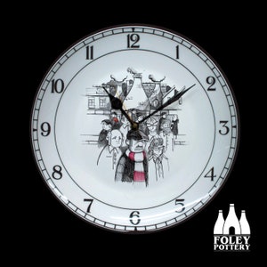 May include: A white ceramic clock with black Roman numeral markings and a black hand. The clock face features a black and white illustration of a group of people standing in front of a building with chimneys. The clock is made by Foley Pottery.