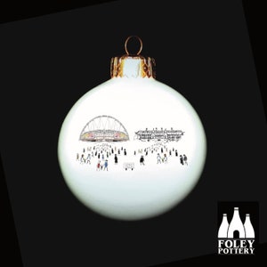 May include: White Christmas ornament with a black and white illustration of Wembley Stadium and a crowd of people. The ornament has a gold top and is made by Foley Pottery.
