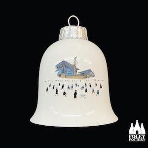 May include: White ceramic Christmas ornament shaped like a bell with a blue and white illustration of a stadium and people walking towards it. The text "FOOTBALL CLUB" is visible on the ornament.