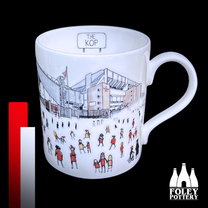 May include: White ceramic mug with a black and white illustration of a stadium and people. The mug has a black handle and the words "The Kop" printed on the top.