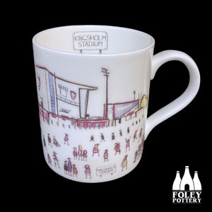 Puede incluir: Taza de cerámica blanca con una ilustración dibujada a mano de un estadio y personas. El estadio está etiquetado como "Kingsholm Stadium".