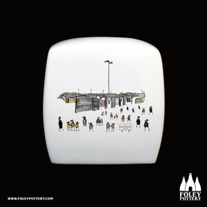 Könnte beinhalten: Weiße Keramiktasse mit einer Schwarzweißillustration eines Schulgebäudes und Menschen, die draußen spazieren gehen. Der Text "The Environment" steht auf einem Schild in der Illustration.