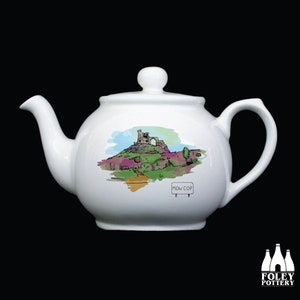 Op de afbeelding: Witte keramische theepot met een handgetekend ontwerp van een kasteel op een heuvel met de tekst "Mow Cop" op een bord.