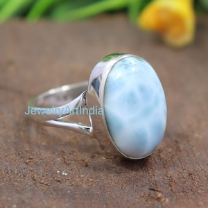 May include: A silver ring with a light blue oval-shaped gemstone. The gemstone has a swirling pattern.