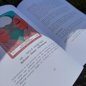 May include: An open book with a tarot card featuring two figures with red skin and a green background. The card reads "SELF-INQUIRY" and the page text discusses individuation and self-reflection.