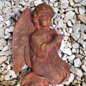 Könnte beinhalten: Eine Terrakotta-Skulptur eines Engels mit Flügeln, kniend und betend. Der Engel ist in Braun- und Rottönen bemalt.