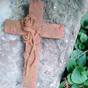 Könnte beinhalten: Ein Terrakotta-Kreuz mit einem geschnitzten Rosenranken-Design. Das Kreuz ist rotbraun und hat einen rustikalen, verwitterten Look.