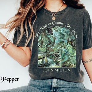 May include: Dark gray t-shirt featuring a detailed illustration from "The Mask of Comus: The Poem" by John Milton. The artwork is in shades of green, blue, and white. The shirt is a relaxed fit and has a vintage look.