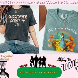 May include: Two t-shirts with Wizard of Oz themes. One is dark gray with "Surrender Dorothy" text and a witch graphic. The other is light green with "Off to cause a kerfuffle" text and a Dorothy graphic.