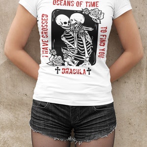 May include: White t-shirt with a black and white graphic of two skeletons embracing. The text "I have crossed oceans of time to find you" and "Dracula" are printed in red on the shirt.