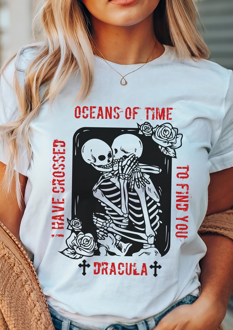 May include: White t-shirt with a black and white graphic of two skeletons embracing. The text "OCEANS OF TIME I HAVE CROSSED TO FIND YOU" is written in red above the graphic. The text "DRACULA" is written in red below the graphic.