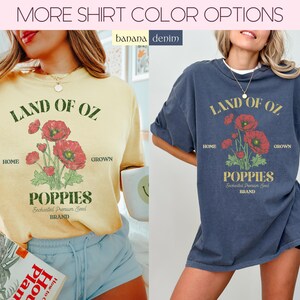 May include: Two t-shirts, one yellow and one navy blue, each with a graphic of red poppies and the text "LAND OF OZ POPPIES." The shirts have a vintage aesthetic, with the text and graphic in a distressed style. The shirts are part of a clothing collection.