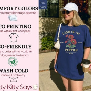 May include: Navy blue t-shirt with a graphic of red poppies and the text "LAND OF OZ POPPIES". The shirt also has the text "HOME" and "GROWN". The shirt is part of the "Witty Kitty Says" brand.