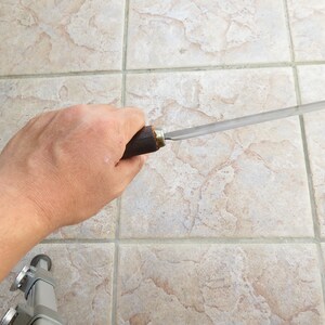 May include: A person holding a long, thin, metal file with a wooden handle. The file is approximately 30 cm long and has a slightly curved blade.