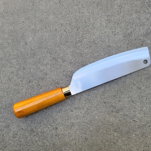May include: A stainless steel cleaver knife with a light brown wooden handle and a gold-coloured bolster. The blade is wide and straight, with a hole near the tip. The knife is designed for chopping and slicing.
