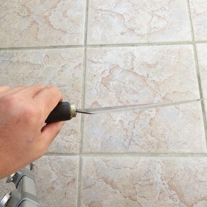 Puede incluir: Una persona sosteniendo un cuchillo largo, delgado y plateado con un mango de madera. El cuchillo es afilado y puntiagudo.