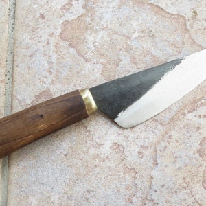 May include: A small, black-handled knife with a wooden handle and a brass accent. The blade is sharp and has a slight curve.