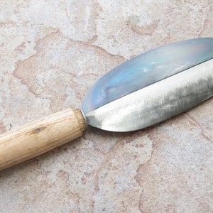 May include: A wooden handled metal knife with a curved blade. The blade is dull and has a slight blue tint.