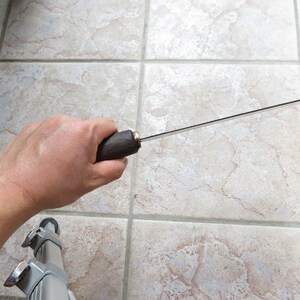May include: A person holding a long, thin, silver knife with a brown wooden handle.