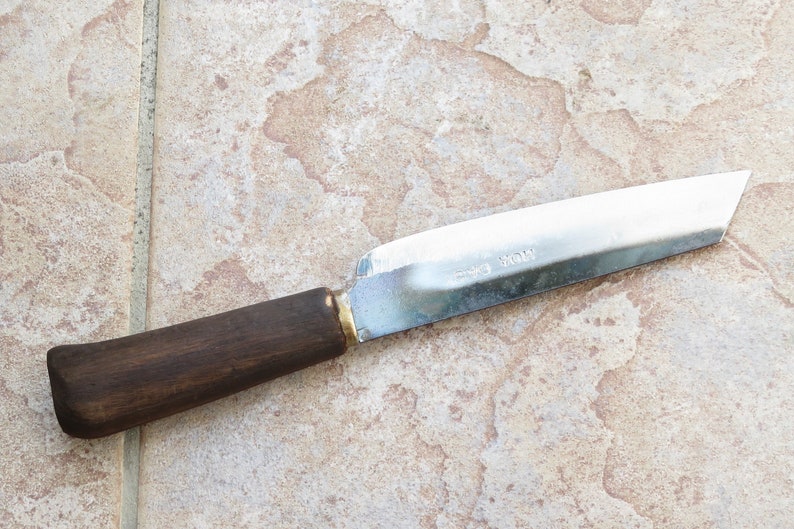 May include: A knife with a brown wooden handle and a silver blade. The blade is etched with the words "Made in Japan".