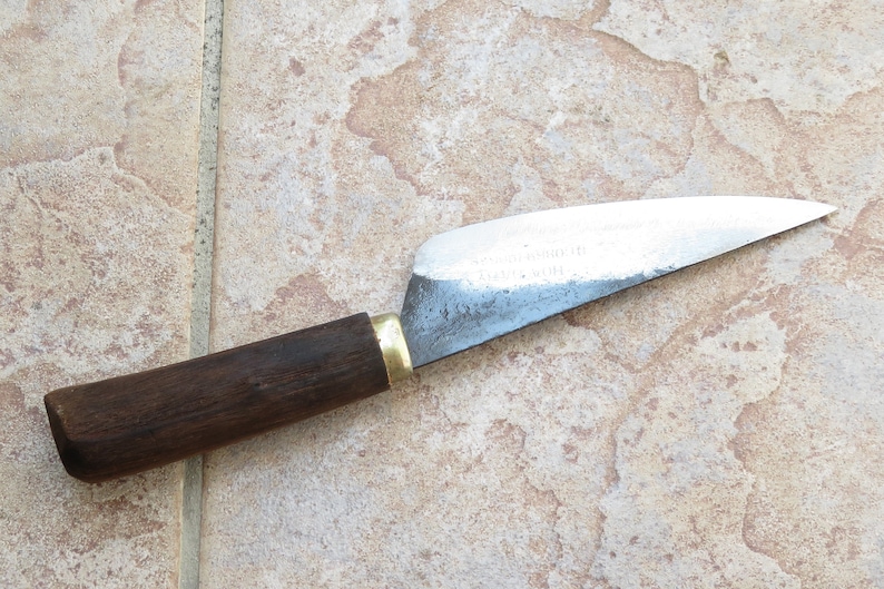 May include: A small, sharp knife with a wooden handle and a metal blade. The blade is slightly curved and has a dull finish. The handle is dark brown and has a brass ferrule.