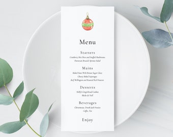 May include: A white menu card with a watercolor Christmas ornament illustration at the top. The menu lists starters, mains, desserts, and beverages. The card is on a white plate with greenery.