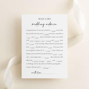 Wedding Advice mad libs game with minimalist design laying on a beige background with a silk ribbon