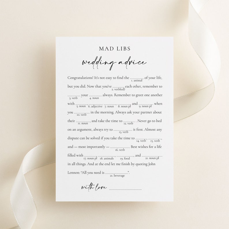 Wedding Advice mad libs game with minimalist design laying on a beige background with a silk ribbon