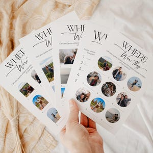 A hand holding 5 "where were they" wedding game cards with modern, minimalist design and beautiful, written calligraphy font