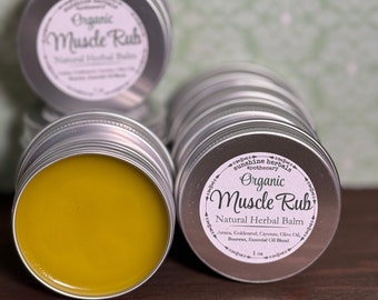 Puede incluir: Una lata plateada con un bálsamo amarillo en su interior. La etiqueta dice "Sunshine Herbals Apothecary Organic Muscle Rub Natural Herbal Balm Arnica, Goldenrod, Cayenne, Olive Oil, Beeswax, Essential Oil Blend 1 oz."