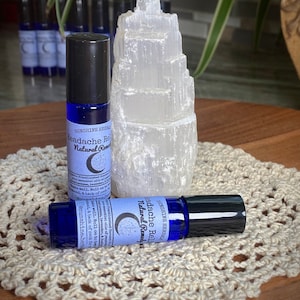Puede incluir: Dos botellas de vidrio azul con tapones negros y etiquetas blancas que dicen "Headache Relief Natural Remedy" con un gr&aacute;fico de luna creciente y estrellas. Las botellas est&aacute;n sobre un encaje blanco de ganchillo.