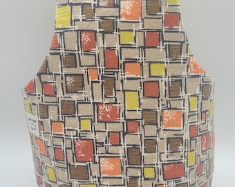 May include: A fabric tote bag with a geometric pattern of squares in shades of brown, orange, yellow, and beige. The bag has a rectangular base and a wide, open top, suitable for carrying items.