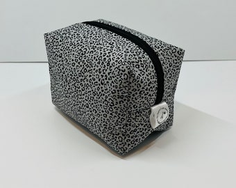May include: A gray and black leopard print zippered pouch with a silver zipper pull.
