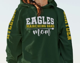 May include: Green hooded sweatshirt with the text "Eagles Marching Band Mom" in gold and silver glitter on the front. The sleeves have the word "Eagles" in gold glitter.