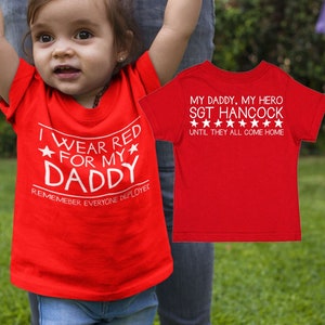 May include: Red t-shirt with white text that says "I wear red for my daddy. Remember everyone deployed." and a red t-shirt with white text that says "My daddy, my hero. Sgt Hancock. Until they all come home."