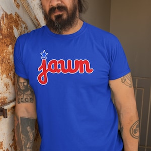 May include: A royal blue t-shirt with a red and white star and the word "Jawn" in red lettering.