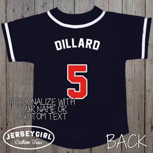 Puede incluir: Una camiseta de b&eacute;isbol azul marino con ribetes blancos y el nombre "Dillard" y el n&uacute;mero "5" en rojo en la espalda. El texto "Personaliza con tu nombre o texto personalizado" est&aacute; impreso debajo del n&uacute;mero. El texto "JerseyGirl Custom Tees" est&aacute; impreso en la parte inferior izquierda y "BACK" est&aacute; impreso en la parte inferior derecha.