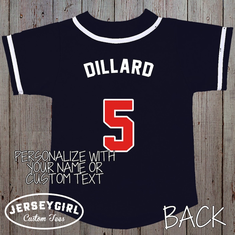 Puede incluir: Una camiseta de b&eacute;isbol azul marino con ribetes blancos y el nombre "Dillard" y el n&uacute;mero "5" en rojo en la espalda. El texto "Personaliza con tu nombre o texto personalizado" est&aacute; impreso debajo del n&uacute;mero. El texto "JerseyGirl Custom Tees" est&aacute; impreso en la parte inferior izquierda y "BACK" est&aacute; impreso en la parte inferior derecha.