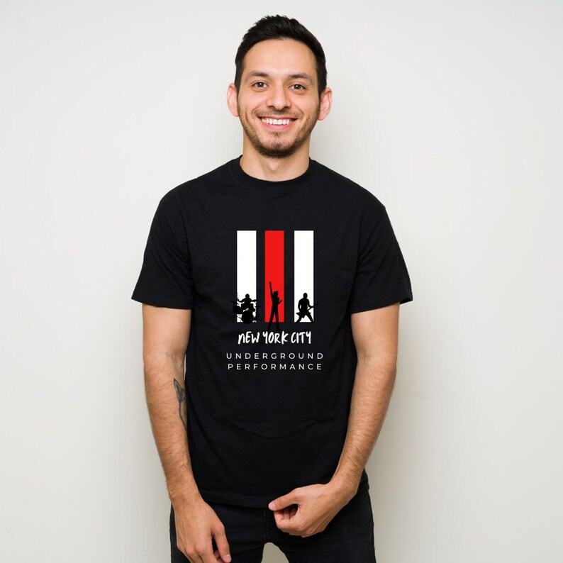 K&ouml;nnte beinhalten: Schwarzes T-Shirt mit einem Grafikdruck einer Band, die auf der B&uuml;hne spielt. Die Grafik ist in Schwarzwei&szlig; mit einem roten Streifen hinter der Band. Der Text "NEW YORK CITY UNDERGROUND PERFORMANCE" ist unterhalb der Grafik aufgedruckt.