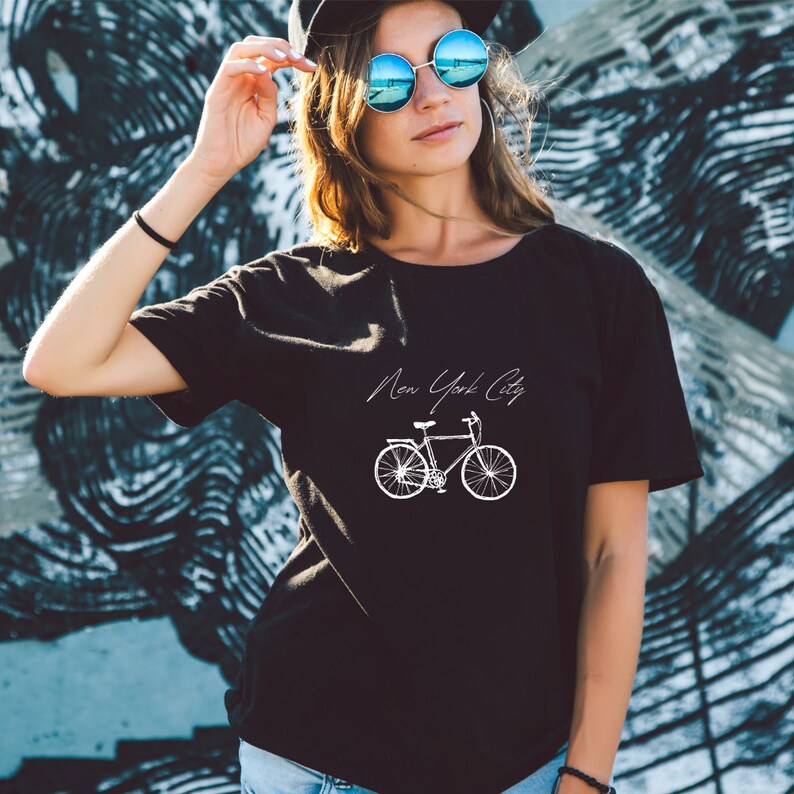 K&ouml;nnte beinhalten: Schwarzes T-Shirt mit einem wei&szlig;en Grafikdruck eines Fahrrads und dem Text "New York City".