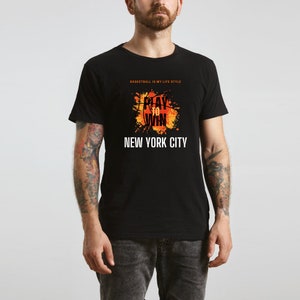 K&ouml;nnte beinhalten: Schwarzes T-Shirt mit einer orangefarbenen und gelben Basketballgrafik und dem Text "Play to Win" und "New York City". Der Text "Basketball is my life style" ist ebenfalls auf dem T-Shirt aufgedruckt.