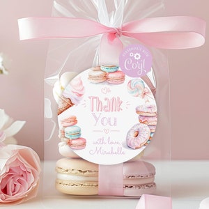 Könnte beinhalten: Eine transparente Plastiktüte gefüllt mit Macarons und einem rosa Band, das oben um die Tüte gebunden ist. Ein runder Aufkleber mit rosa Hintergrund und weißem Text lautet "Danke mit Liebe, Mirabelle". Ein kleinerer Aufkleber mit lila Hintergrund und weißem Text lautet "Personalisiert mit Coryl".