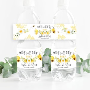 Op de afbeelding: Waterfleslabels met een bijen thema. De labels hebben een gele en zwarte bij, witte madeliefjes en honingraatpatronen. De tekst op de labels luidt "What will baby bee?" en "Sophie & Alex's Gender Reveal."