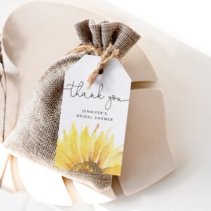 May include: A white thank you tag with a watercolor sunflower design. The tag says "Thank you" and "Jennifer's Bridal Shower".