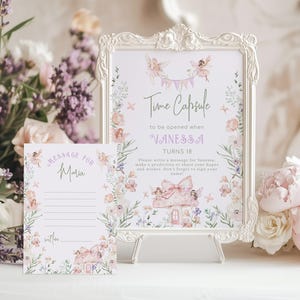 Puede incluir: Un letrero enmarcado y una tarjeta con ilustraciones florales y de hadas. El letrero dice "Time Capsule" y "Vanessa cumple 18 años". La tarjeta dice "Mensaje para Maria". Los tonos rosa y morado dominan el diseño, con flores decorativas.