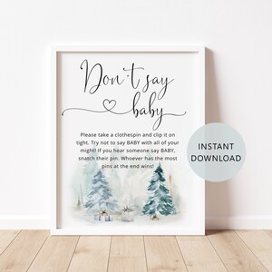 Puede incluir: Señal imprimible para un juego de baby shower. La señal es blanca con texto negro que dice "No digas bebé". El fondo es una ilustración de acuarela de un bosque de invierno con dos pinos y regalos.