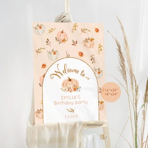 May include: A welcome sign for a birthday party with a peach background and a gold glitter arch. The sign features a pumpkin with flowers and leaves, and the text "Welcome to Emilia's Birthday Party 3.3.2025". The sign is available in two sizes: 16"x20" and 18"x24".