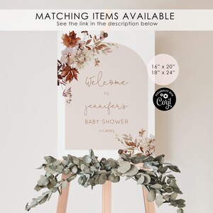 May include: Welcome to Jennifer's Baby Shower sign with a watercolor floral design in shades of brown, pink, and white. The sign is on a wooden easel and has the text "Welcome to Jennifer's Baby Shower 1.1.2025" and the sizes "16" x 20" and 18" x 24".