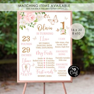 May include: A pink and gold first birthday milestone poster with a floral design and butterflies. The poster includes the child's name, Olivia, and details about their first year, including weight, height, milestones, favorite song, and favorite food.